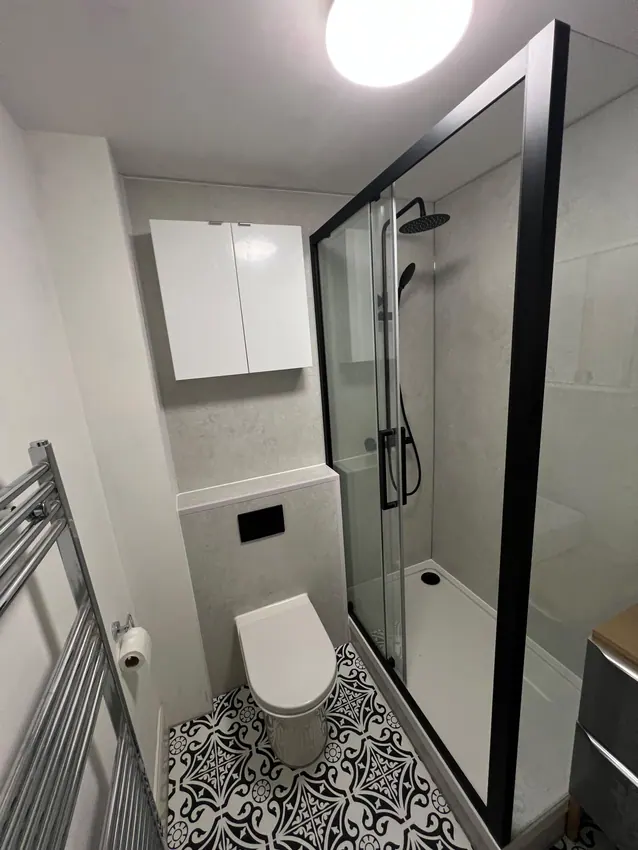 Compact shower room with black screen, toilet and patterned flooring