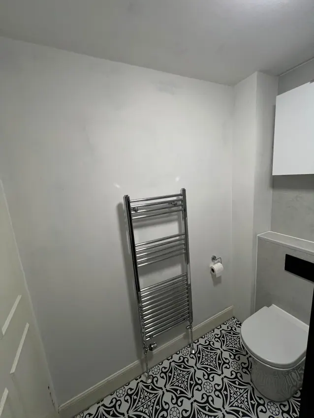 Chrome towel rail beside a toilet and patterned floor