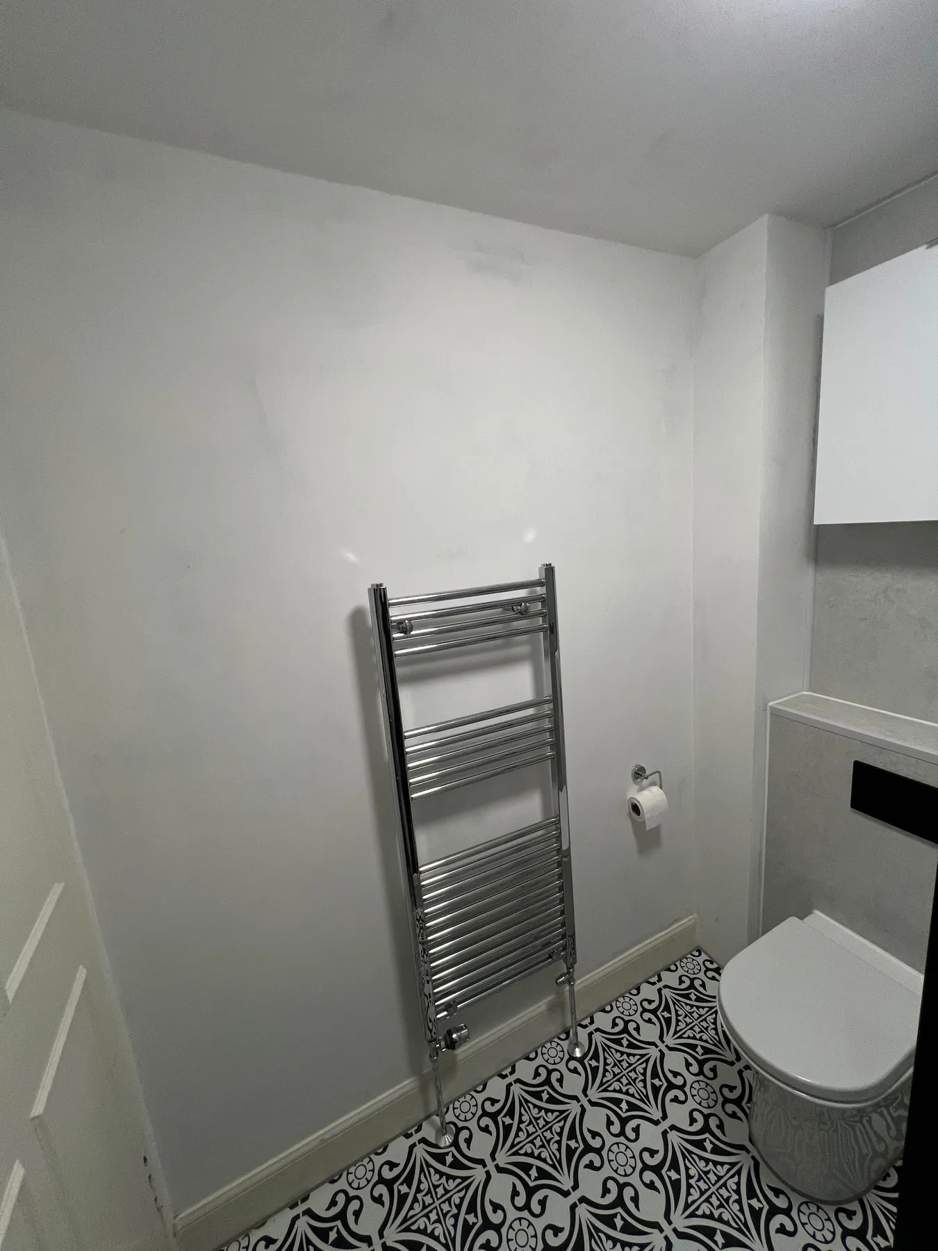 Chrome towel rail beside a toilet and patterned floor