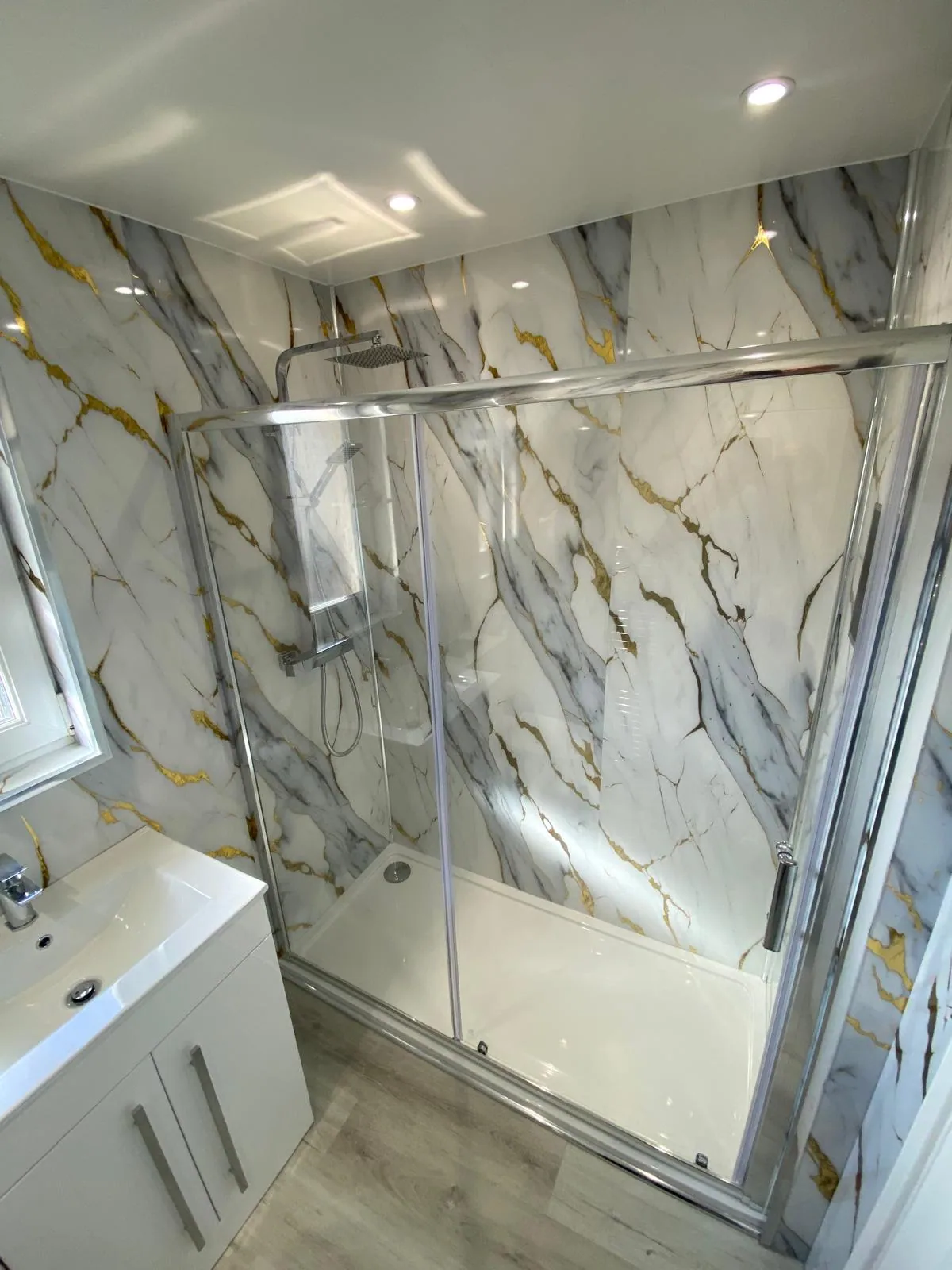 Chrome shower enclosure with marble-effect panels and white vanity