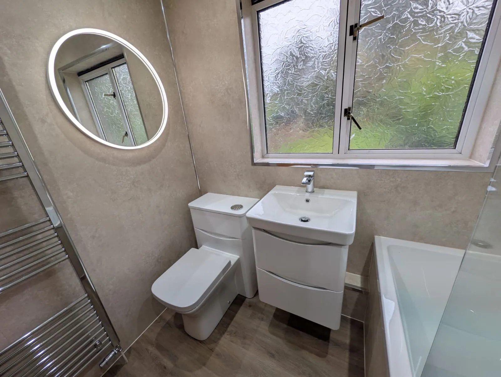 White curved drawer vanity, toilet and illuminated round mirror